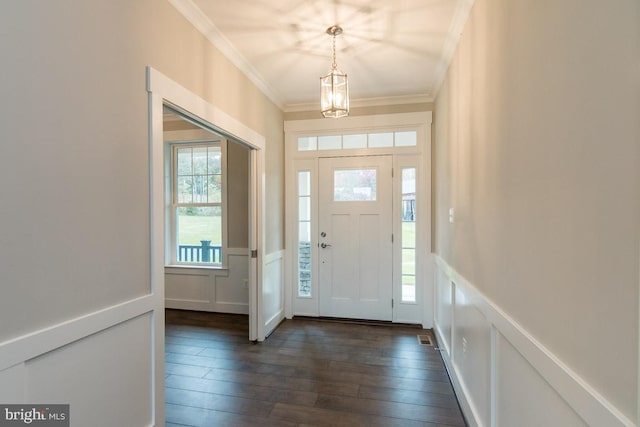 foyer with plenty of natural light, ornamental molding, a notable chandelier, and dark hardwood / wood-style flooring