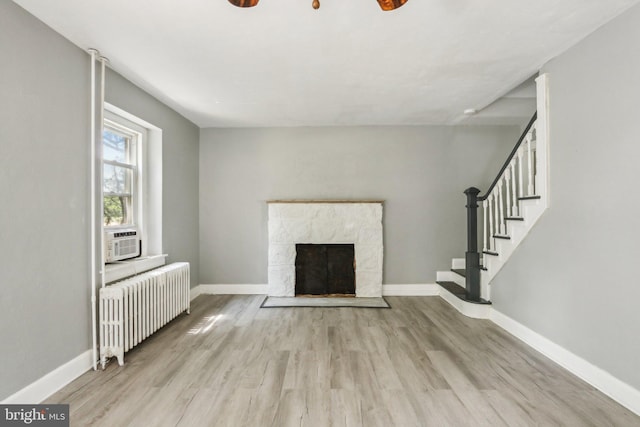 unfurnished living room with cooling unit, radiator heating unit, and light hardwood / wood-style flooring