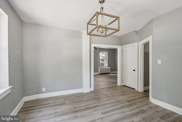 interior space featuring radiator heating unit, a chandelier, and light hardwood / wood-style flooring