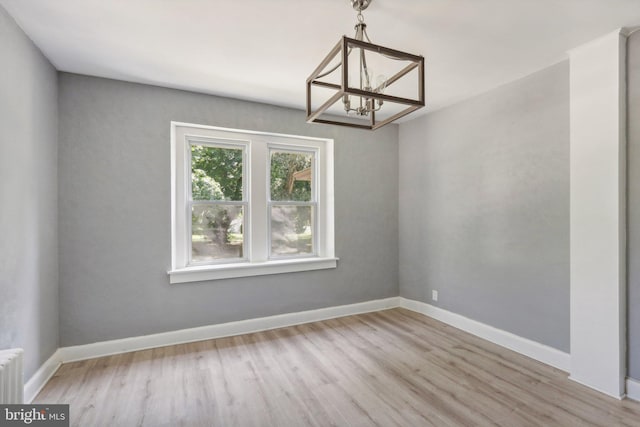 interior space with an inviting chandelier, radiator heating unit, and light hardwood / wood-style floors