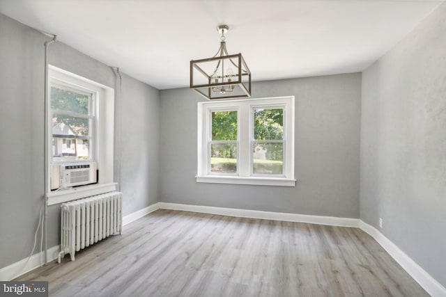 unfurnished dining area with cooling unit, plenty of natural light, radiator, and light wood-type flooring