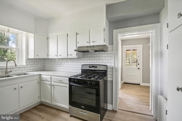 kitchen featuring radiator, sink, black range with gas cooktop, backsplash, and white cabinets