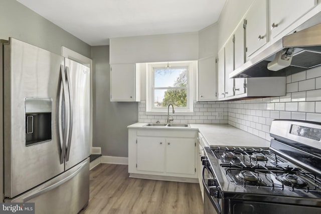 kitchen featuring sink, light hardwood / wood-style flooring, appliances with stainless steel finishes, white cabinetry, and backsplash