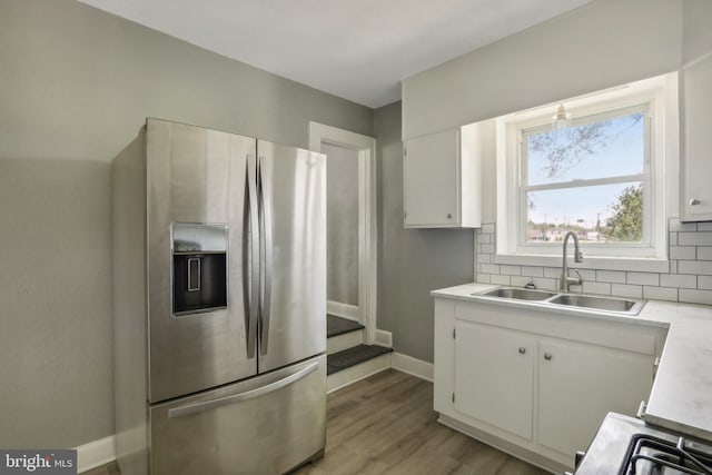 kitchen featuring white cabinetry, sink, backsplash, and stainless steel fridge