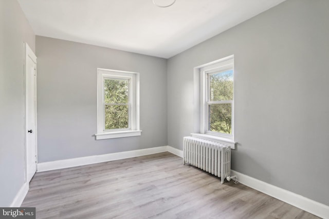 spare room with radiator heating unit and light wood-type flooring