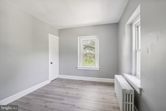 spare room with radiator heating unit and light hardwood / wood-style floors