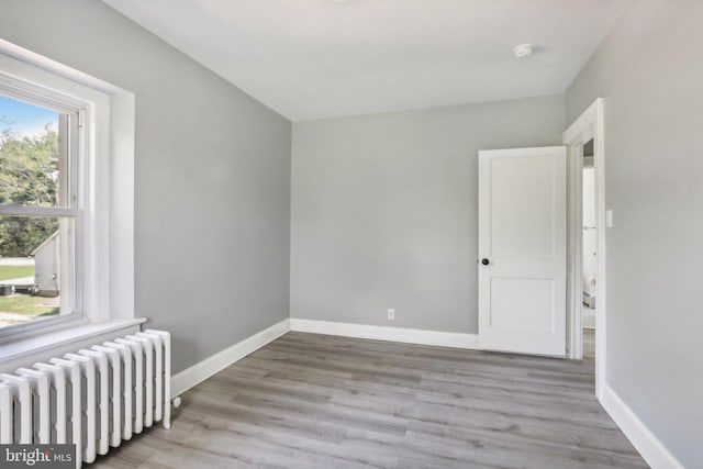 unfurnished room featuring radiator heating unit and light wood-type flooring