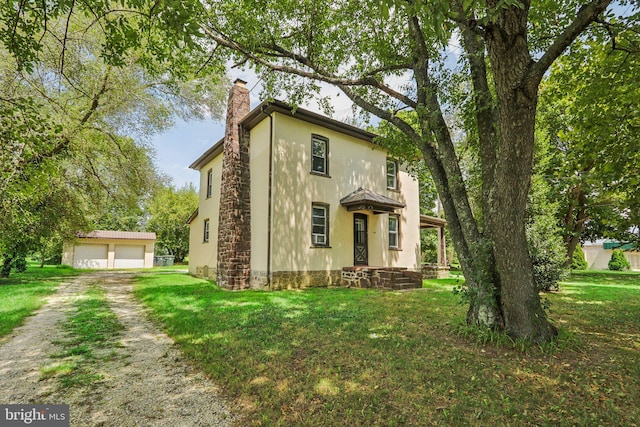 view of front of property featuring a garage, an outdoor structure, and a front yard