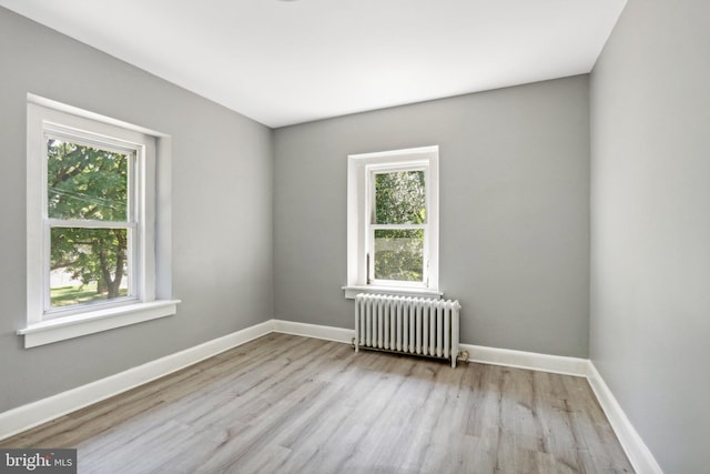 unfurnished room with radiator and light wood-type flooring