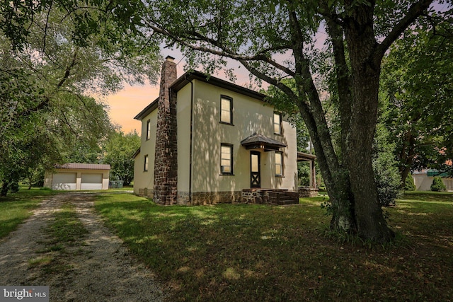 view of front facade featuring a garage, an outdoor structure, and a lawn