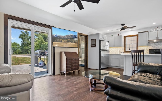 living room featuring dark wood-type flooring and ceiling fan