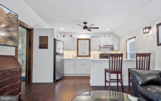 kitchen with stainless steel refrigerator, white cabinetry, sink, and decorative backsplash