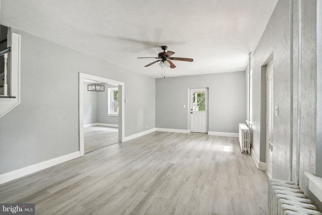 interior space with ceiling fan, radiator, and light wood-type flooring