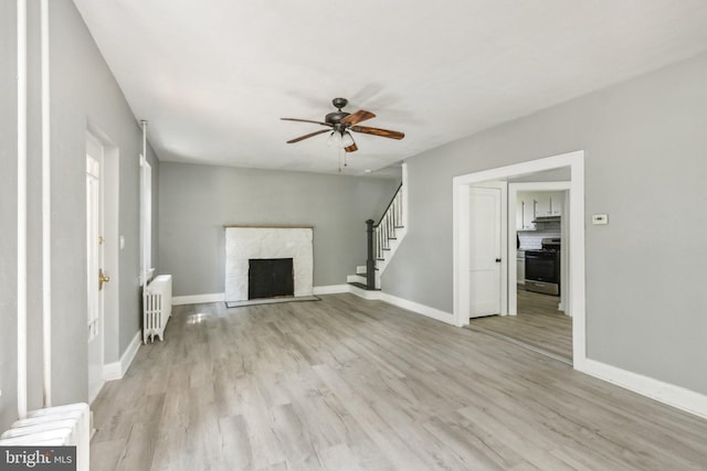 unfurnished living room with ceiling fan, radiator heating unit, and light hardwood / wood-style flooring