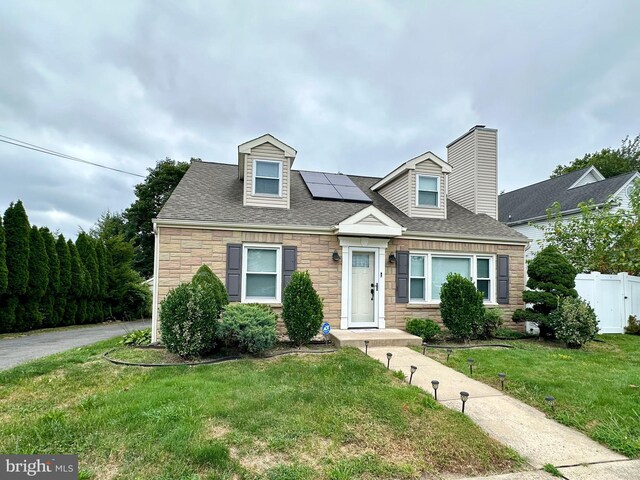 cape cod house with solar panels and a front yard