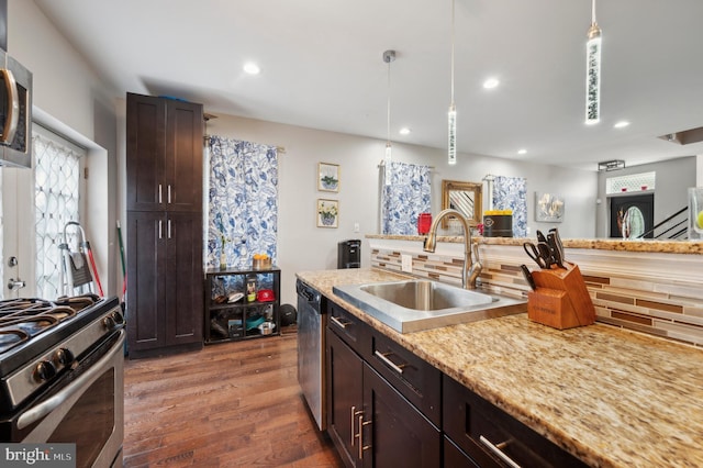 kitchen featuring decorative light fixtures, sink, decorative backsplash, dark brown cabinetry, and stainless steel appliances