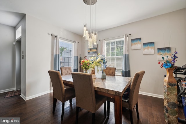 dining room with dark hardwood / wood-style flooring, a wealth of natural light, and an inviting chandelier