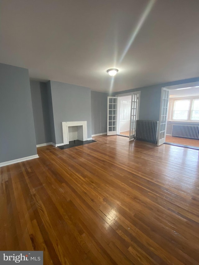 unfurnished living room featuring radiator and dark hardwood / wood-style floors