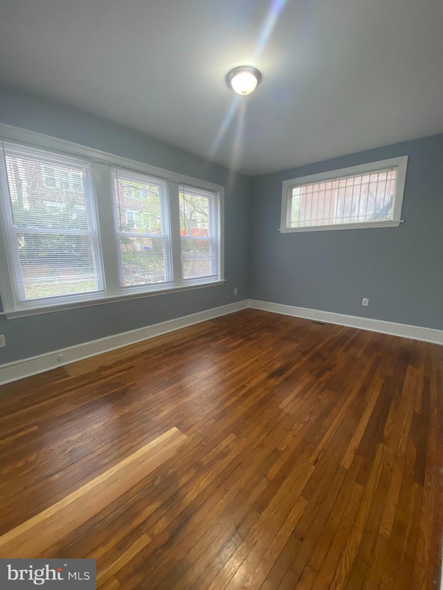 unfurnished room with dark hardwood / wood-style floors and a healthy amount of sunlight