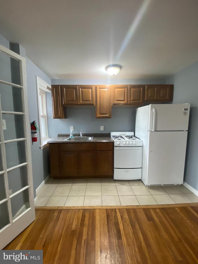 kitchen with light wood-type flooring, white appliances, and sink