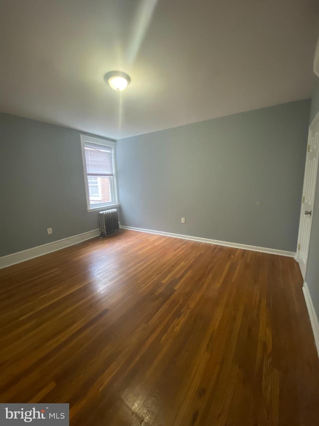 empty room featuring radiator and dark wood-type flooring