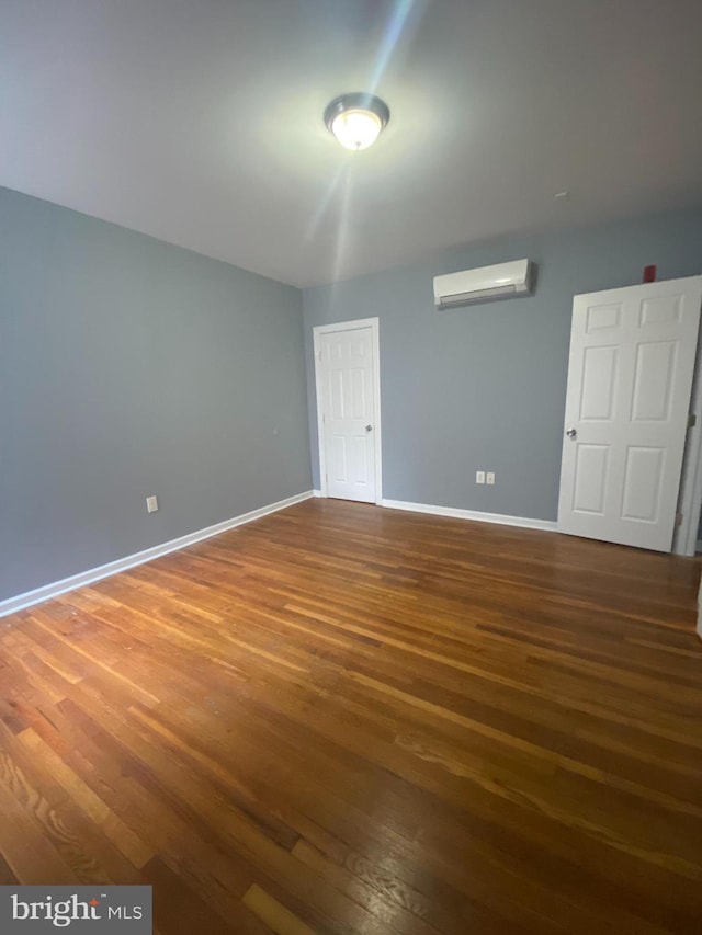 spare room with an AC wall unit and dark hardwood / wood-style floors