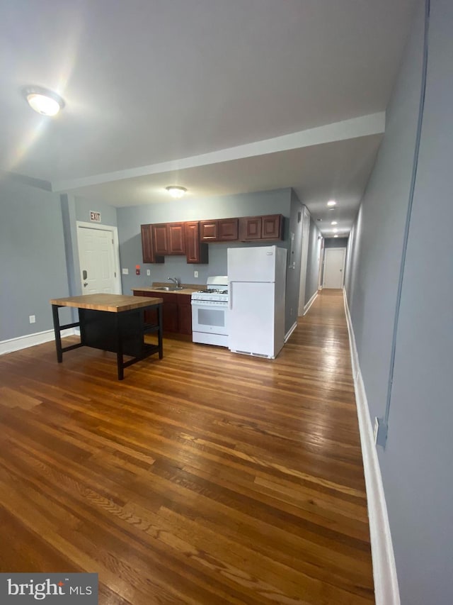 kitchen featuring sink, dark wood-type flooring, and white appliances