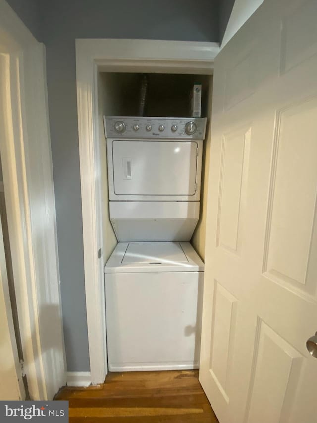 laundry area with stacked washer and dryer and dark hardwood / wood-style floors