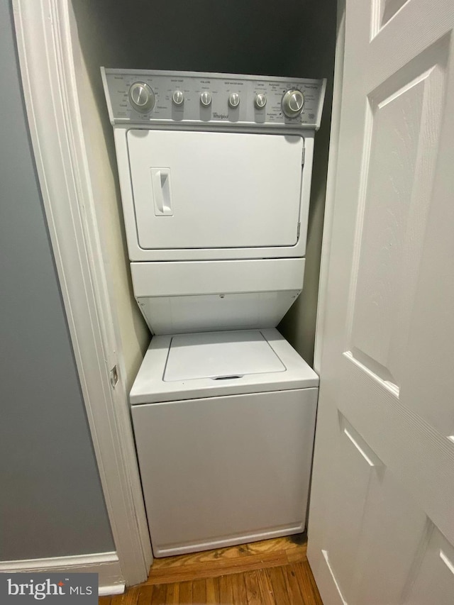 laundry room featuring hardwood / wood-style floors and stacked washer and clothes dryer