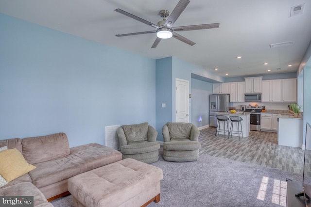 carpeted living room with ceiling fan