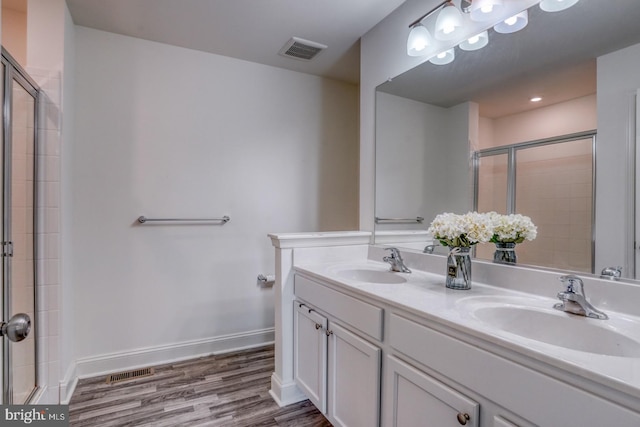 bathroom featuring hardwood / wood-style floors, double sink vanity, and a shower with shower door