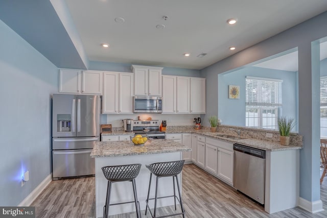 kitchen featuring a center island, stainless steel appliances, light hardwood / wood-style flooring, and white cabinets