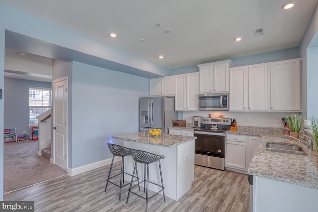 kitchen with light colored carpet, white cabinets, sink, a center island, and stainless steel appliances