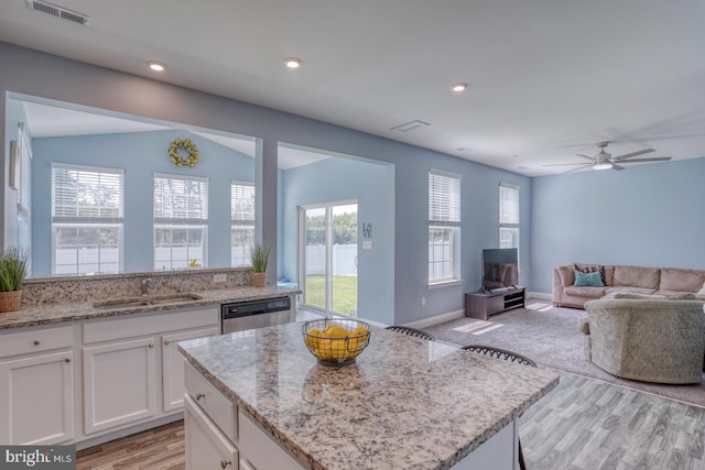 kitchen featuring light hardwood / wood-style floors, white cabinetry, stainless steel dishwasher, a kitchen island, and ceiling fan