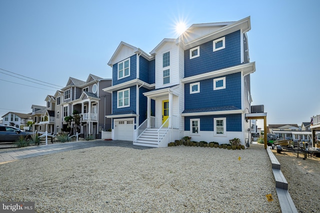 view of front of property featuring a garage, a residential view, cooling unit, and driveway