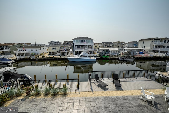 property view of water with a boat dock, a residential view, and fence