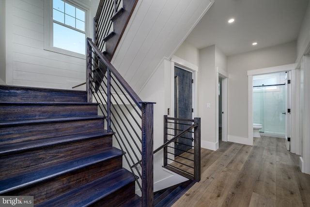 stairway featuring baseboards, wood finished floors, and recessed lighting