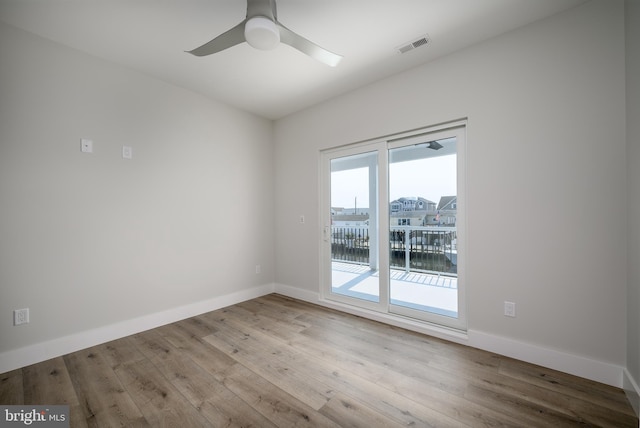 empty room featuring ceiling fan, light wood finished floors, a water view, and baseboards