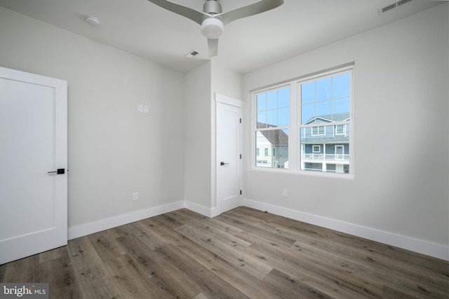 empty room with a ceiling fan, visible vents, baseboards, and wood finished floors