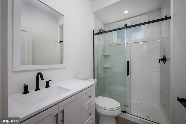 bathroom with a stall shower, vanity, and toilet