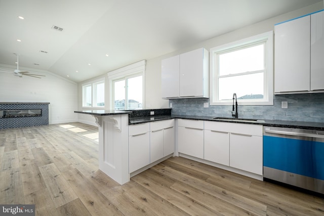 kitchen featuring dishwasher, open floor plan, a sink, and white cabinetry