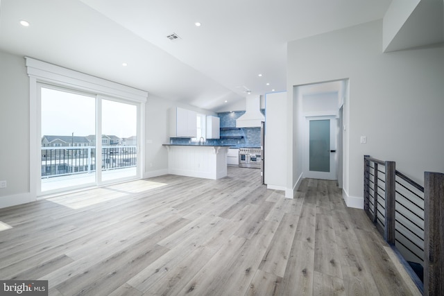 kitchen featuring white cabinets, open floor plan, backsplash, dark countertops, and a kitchen bar