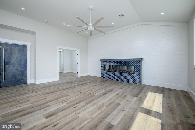 unfurnished living room featuring lofted ceiling, visible vents, light wood-style flooring, ceiling fan, and a tile fireplace