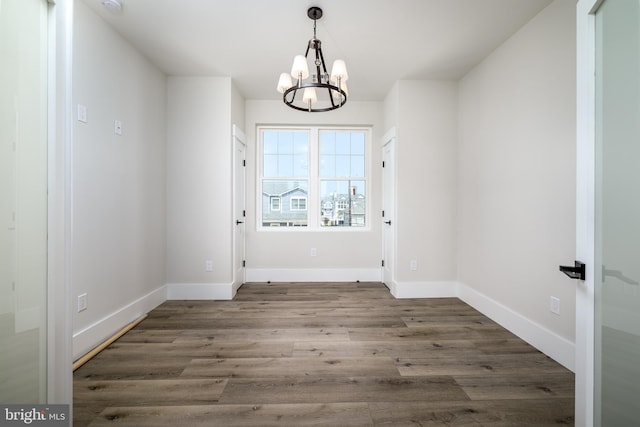 doorway with dark wood-style floors, an inviting chandelier, and baseboards