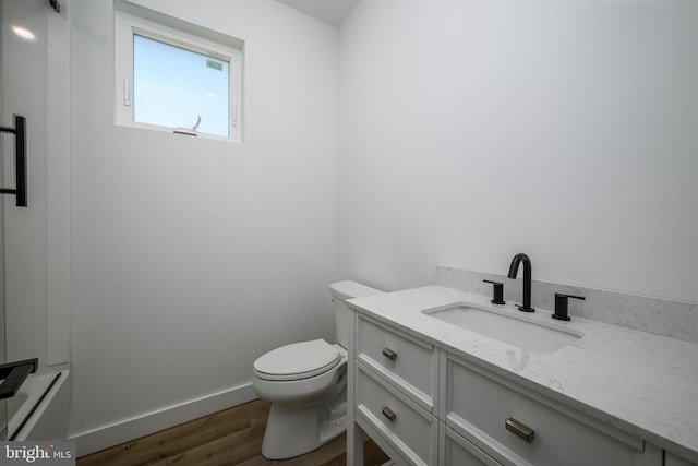 bathroom with baseboards, vanity, toilet, and wood finished floors