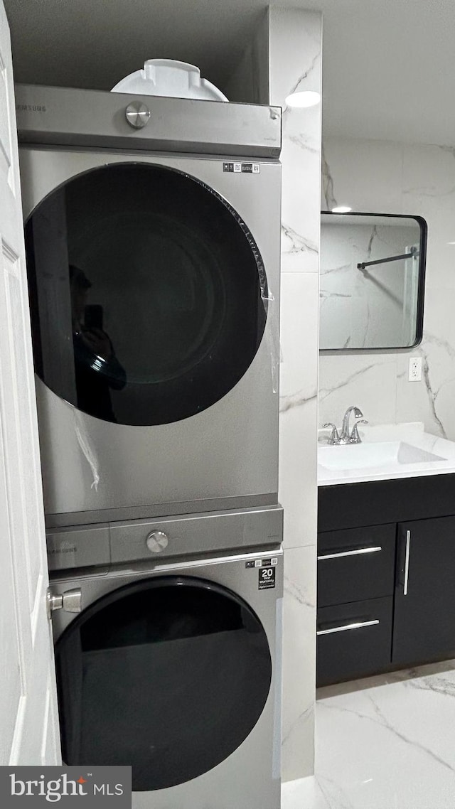 laundry area featuring light tile patterned flooring, sink, and stacked washer and clothes dryer