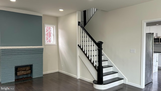 staircase with dark hardwood / wood-style flooring and a brick fireplace