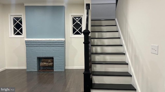 stairs with hardwood / wood-style flooring and a brick fireplace