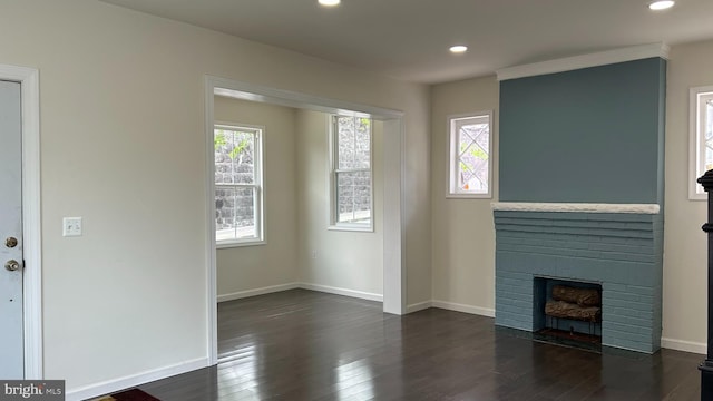 unfurnished living room featuring dark hardwood / wood-style flooring and a brick fireplace