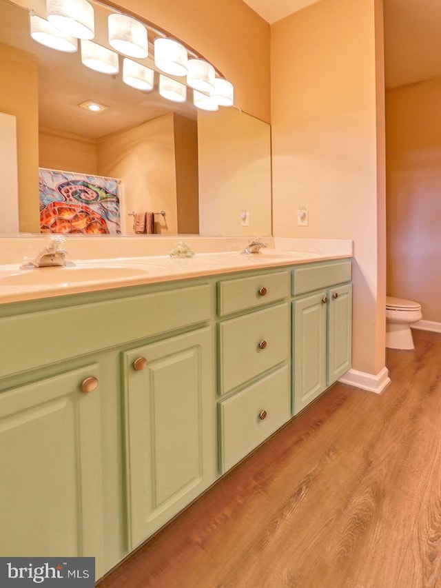 bathroom with wood-type flooring, vanity, and toilet